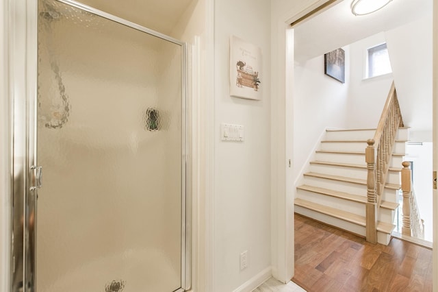 full bathroom with a stall shower, wood finished floors, and baseboards