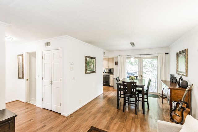 dining room with french doors, visible vents, crown molding, and light wood finished floors