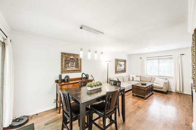 dining area featuring crown molding, light wood-style flooring, and baseboards