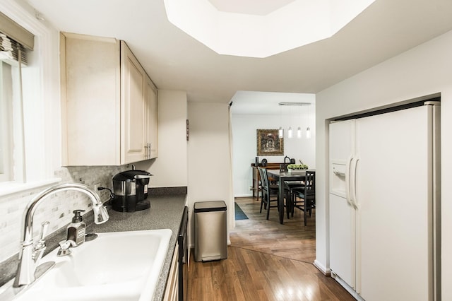 kitchen with dark wood-type flooring, a sink, backsplash, white fridge with ice dispenser, and dark countertops