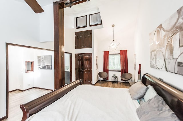 bedroom with a towering ceiling and light wood-type flooring