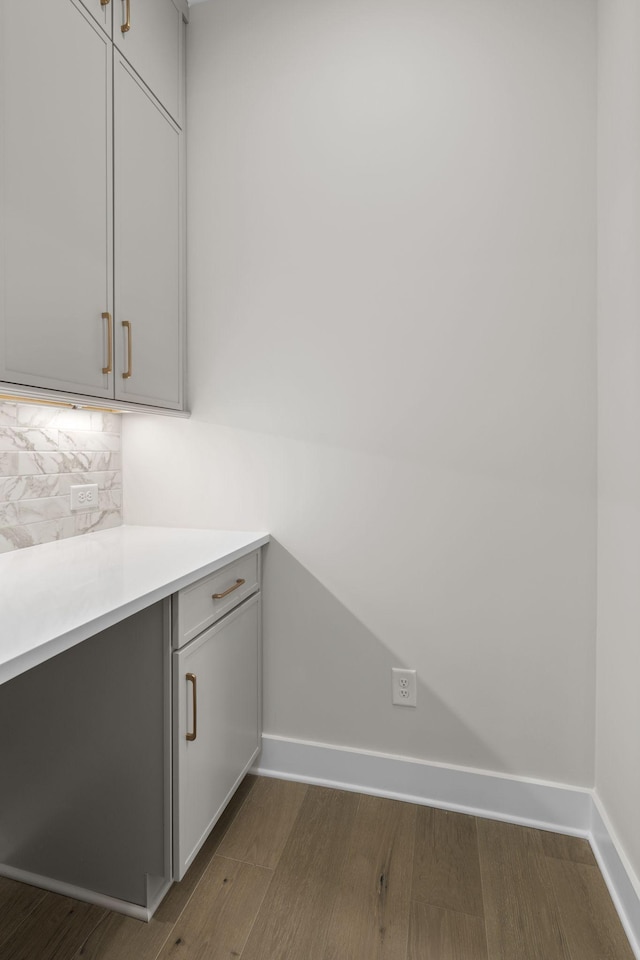 interior space featuring tasteful backsplash, dark wood finished floors, and baseboards