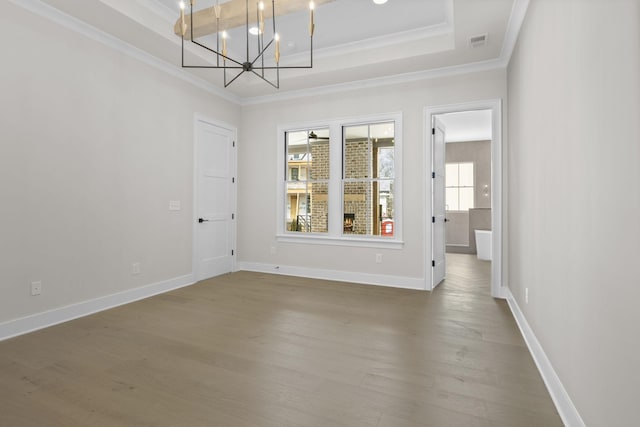 empty room featuring ornamental molding, a raised ceiling, visible vents, and wood finished floors