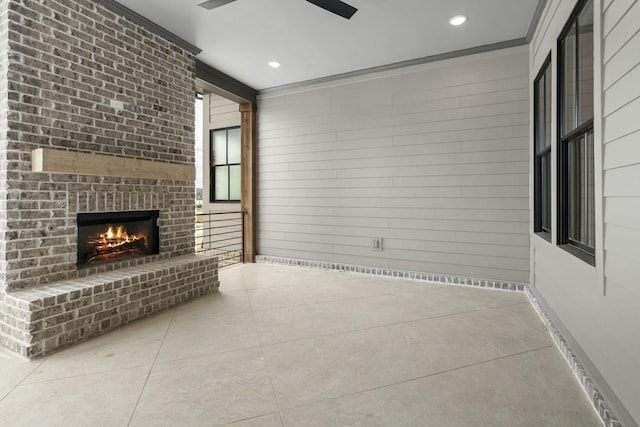 unfurnished living room featuring light tile patterned floors, wood walls, a fireplace, and crown molding