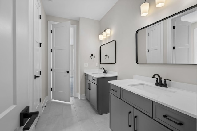 full bathroom featuring two vanities, a sink, and baseboards