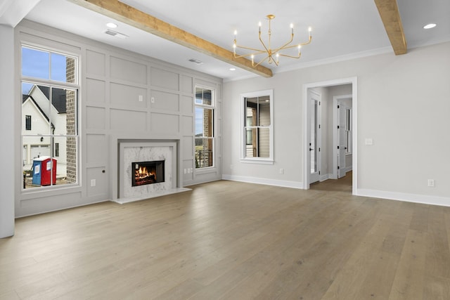 unfurnished living room featuring light wood-type flooring, visible vents, beamed ceiling, and baseboards