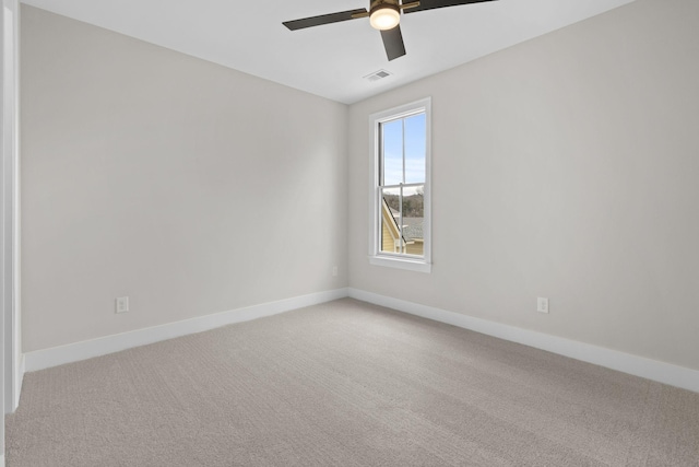 carpeted spare room with visible vents, ceiling fan, and baseboards