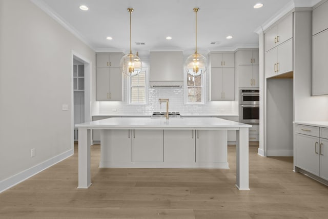 kitchen with light countertops, a center island with sink, and wall chimney range hood