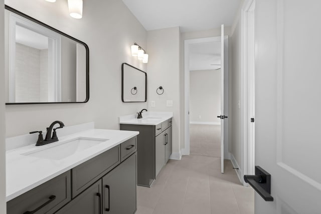 bathroom featuring baseboards, two vanities, a sink, and tile patterned floors