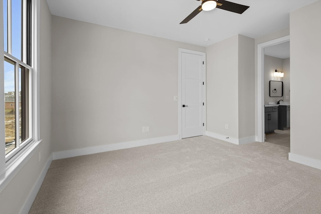 unfurnished bedroom with light carpet, ceiling fan, baseboards, and ensuite bathroom