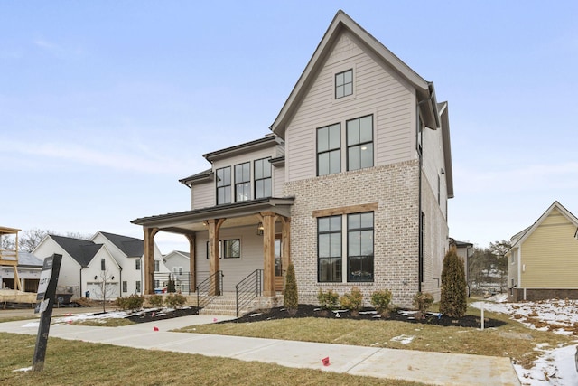 view of front facade featuring a front yard, covered porch, and brick siding