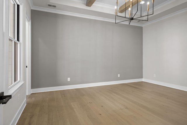 empty room with visible vents, ornamental molding, wood finished floors, a chandelier, and baseboards