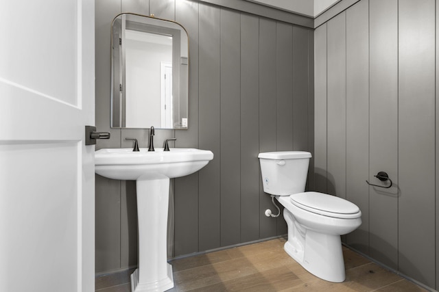 half bath with a sink, toilet, and wood finished floors