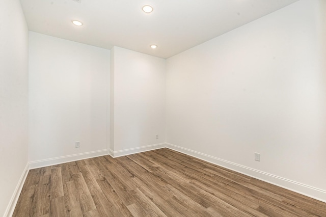 unfurnished room featuring baseboards, wood finished floors, and recessed lighting