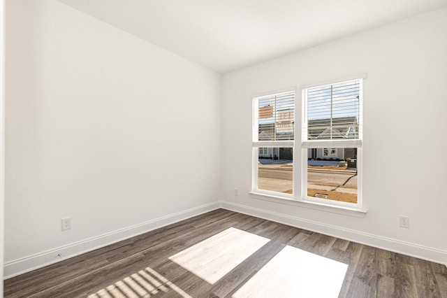 unfurnished room featuring dark wood-type flooring and baseboards