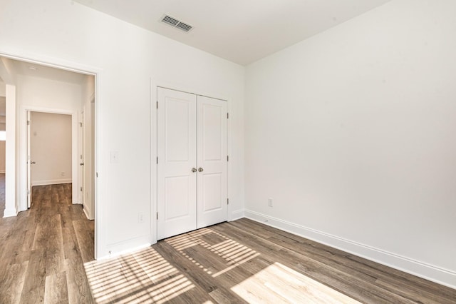 unfurnished bedroom featuring wood finished floors, visible vents, and baseboards