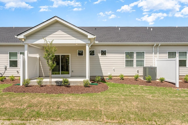 rear view of property with a patio, a lawn, cooling unit, and roof with shingles