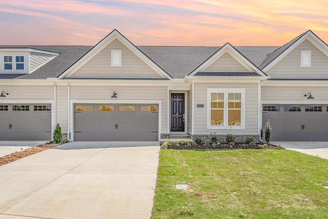 view of front of home featuring concrete driveway, roof with shingles, an attached garage, and a front yard