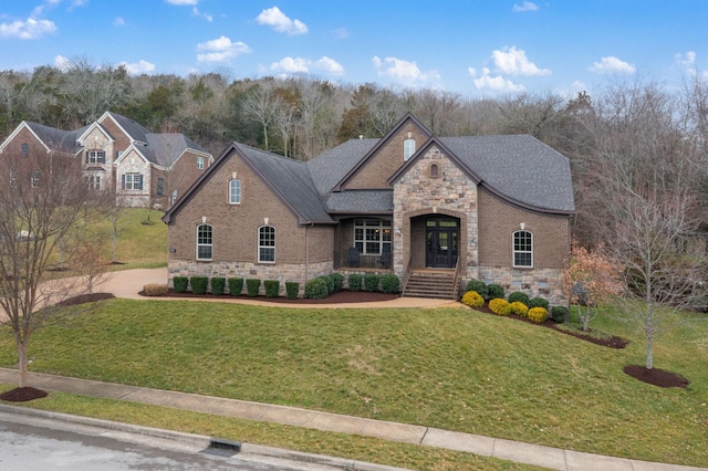 view of front of property with stone siding, a shingled roof, a front lawn, and brick siding