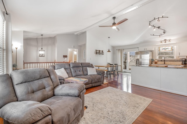 living area featuring dark wood-style flooring, vaulted ceiling, and ceiling fan with notable chandelier