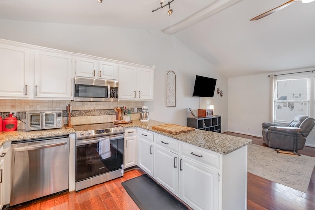 kitchen featuring appliances with stainless steel finishes, open floor plan, white cabinets, and a peninsula