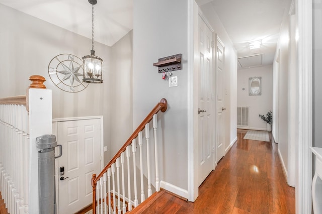 hall with wood finished floors, visible vents, baseboards, an upstairs landing, and attic access