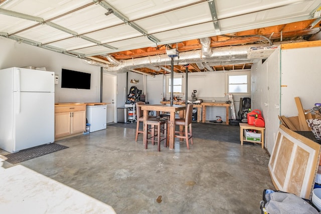 garage featuring a workshop area, freestanding refrigerator, and a garage door opener