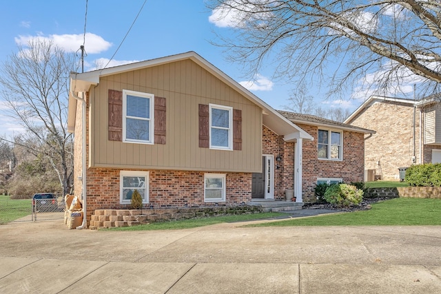 bi-level home with brick siding, fence, and driveway