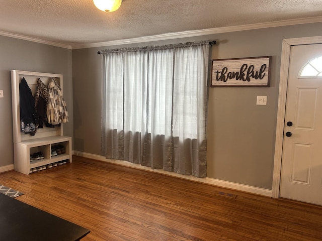 entrance foyer with baseboards, visible vents, wood finished floors, crown molding, and a textured ceiling