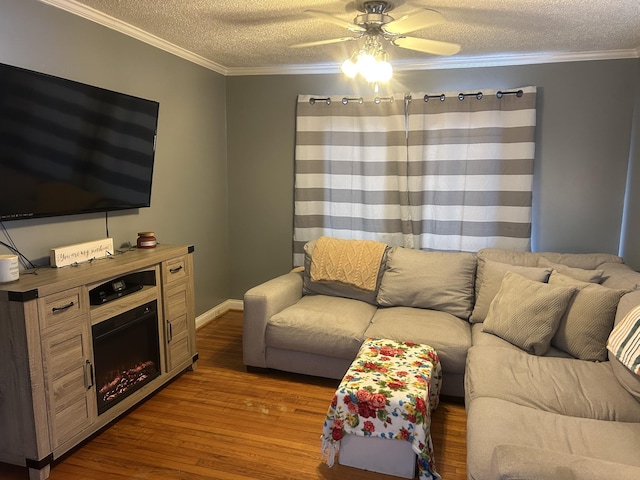 living room featuring a textured ceiling, ceiling fan, dark wood-type flooring, a fireplace, and crown molding