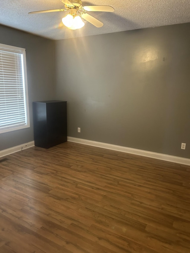 spare room with a ceiling fan, a textured ceiling, baseboards, and dark wood-style flooring