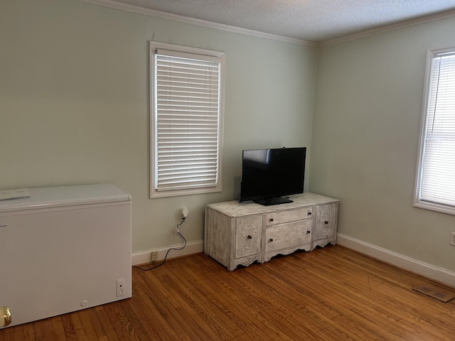 interior space with crown molding, fridge, baseboards, and light wood-style floors