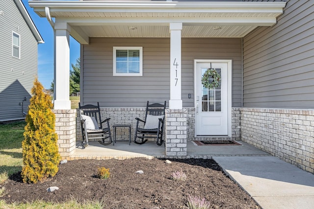 property entrance featuring covered porch and brick siding