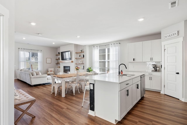 kitchen featuring dark wood-style floors, a large fireplace, visible vents, and a sink