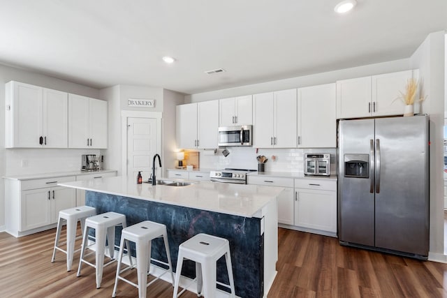 kitchen featuring a breakfast bar area, appliances with stainless steel finishes, dark wood-style flooring, and a sink