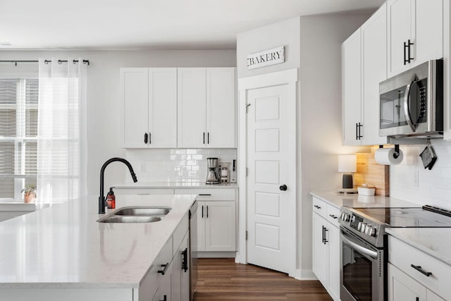 kitchen featuring appliances with stainless steel finishes, a sink, a center island with sink, and white cabinets