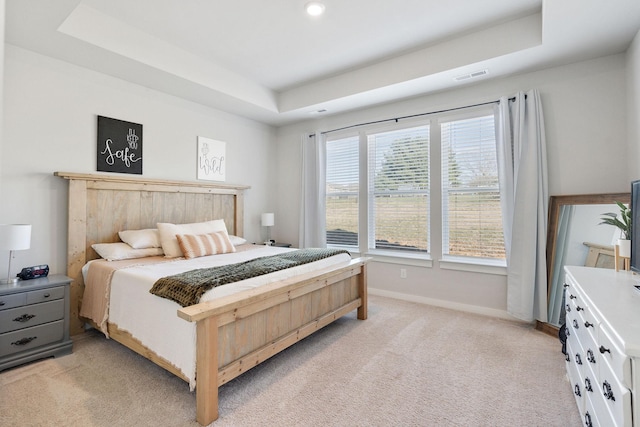 bedroom with visible vents, baseboards, a raised ceiling, and light colored carpet