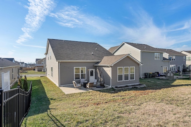 rear view of house featuring a patio, a residential view, roof with shingles, fence, and a yard