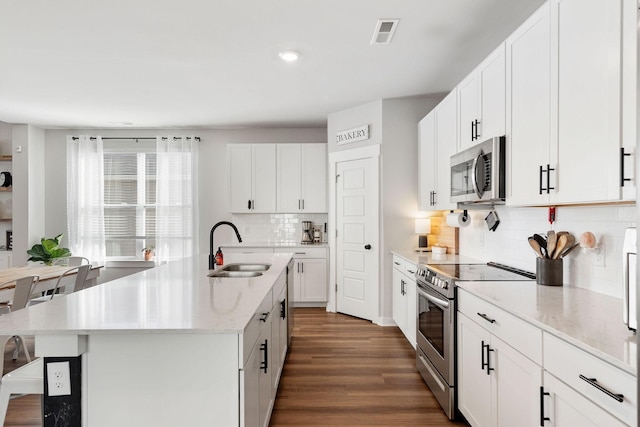 kitchen featuring dark wood-style floors, visible vents, appliances with stainless steel finishes, white cabinets, and a sink