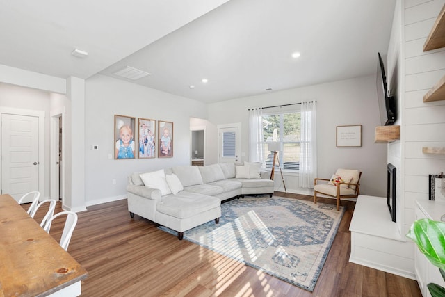 living area with visible vents, a fireplace, baseboards, and wood finished floors