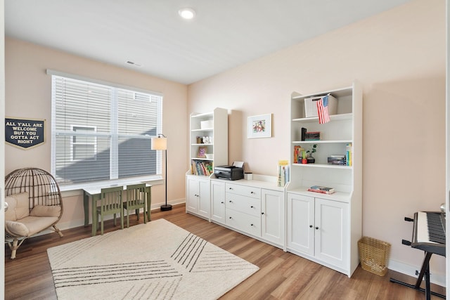 living area featuring light wood-type flooring, visible vents, and baseboards