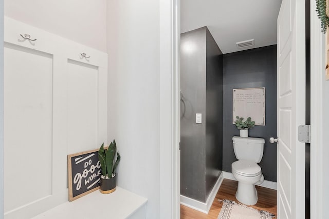 bathroom featuring toilet, baseboards, visible vents, and wood finished floors