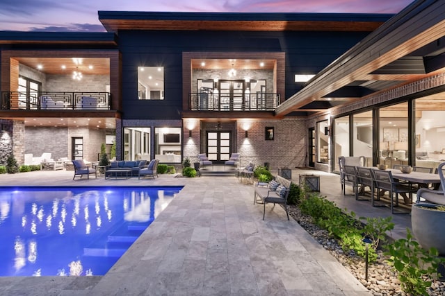 pool at dusk featuring outdoor lounge area, an outdoor pool, french doors, and a patio