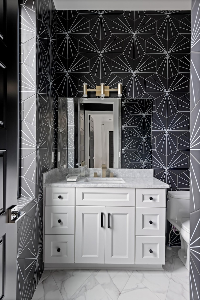 bathroom with marble finish floor, vanity, and toilet