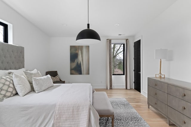 bedroom featuring light wood-style floors, visible vents, and baseboards