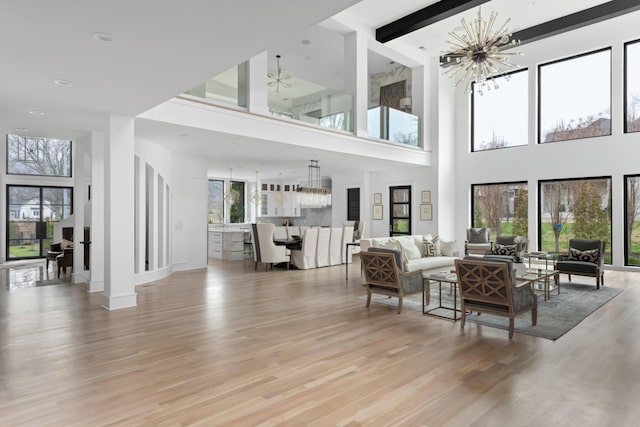 living area featuring light wood-type flooring, an inviting chandelier, and baseboards