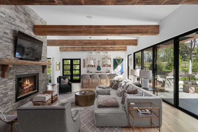 living area featuring light wood-style floors, a fireplace, and beamed ceiling