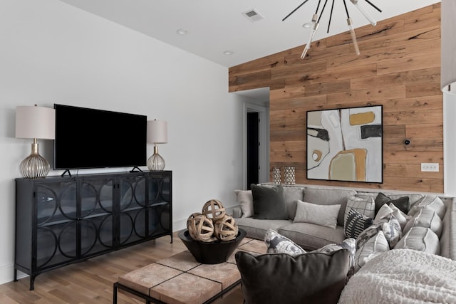 living area featuring lofted ceiling, visible vents, wood walls, and light wood-style flooring