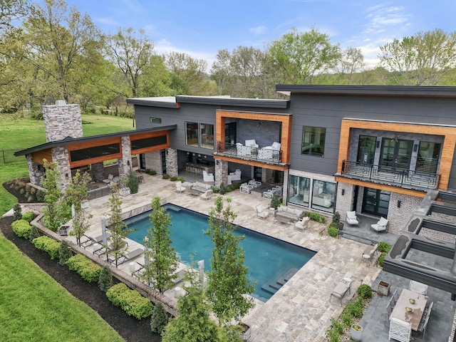 rear view of property featuring a patio area, an outdoor pool, and an outdoor bar