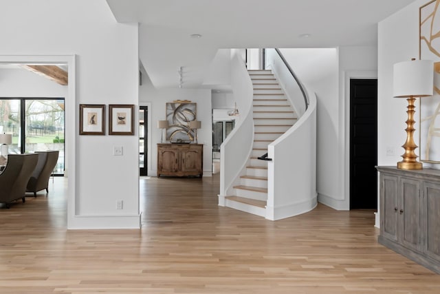 foyer with stairs, light wood finished floors, and baseboards